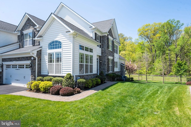 view of side of home with a lawn, fence, driveway, and stone siding
