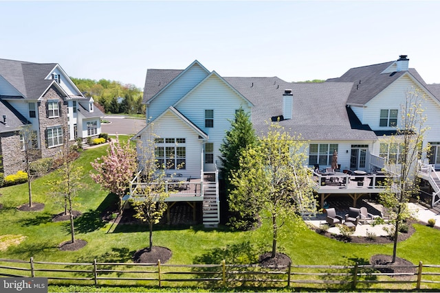 back of property with a chimney, a lawn, a wooden deck, fence private yard, and stairs