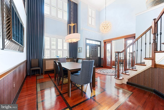 dining room featuring crown molding, dark wood-style flooring, a towering ceiling, and stairway