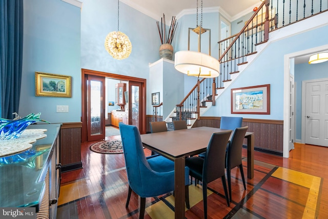 dining room with wood-type flooring, a high ceiling, ornamental molding, and stairway