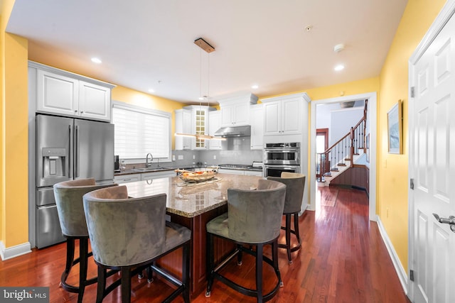 kitchen featuring a sink, under cabinet range hood, white cabinets, and stainless steel appliances