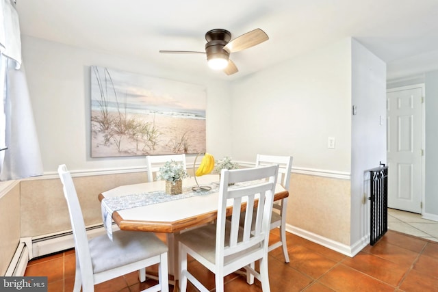 tiled dining space featuring a baseboard heating unit, a ceiling fan, and baseboards