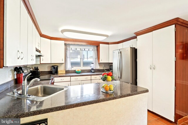 kitchen with a peninsula, a sink, freestanding refrigerator, and dark countertops