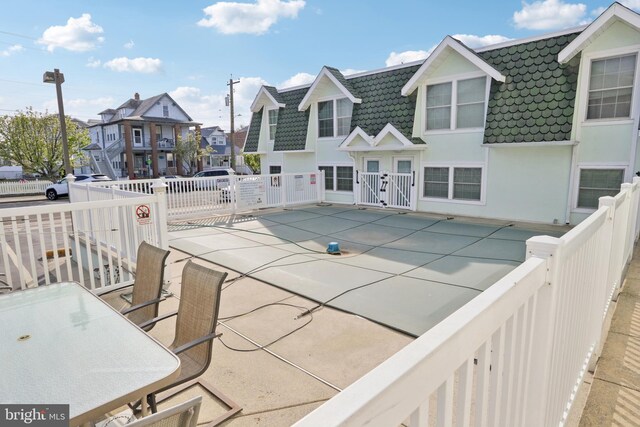 view of swimming pool featuring a gate, fence, a residential view, and a patio
