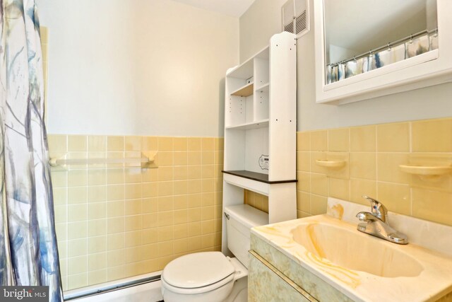 full bath featuring tile walls, vanity, toilet, visible vents, and baseboard heating
