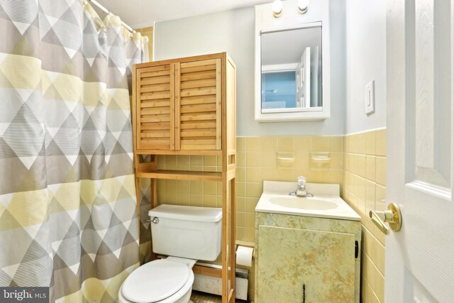 full bathroom with wainscoting, tile walls, toilet, vanity, and curtained shower