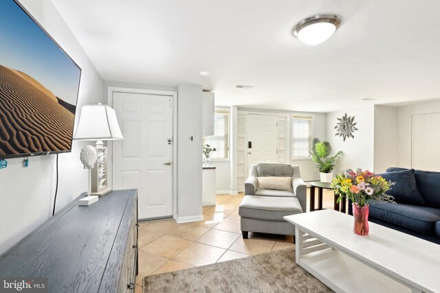 living area with light tile patterned flooring, visible vents, and baseboards