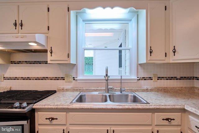 kitchen with stainless steel range with gas stovetop, a sink, under cabinet range hood, and white cabinets