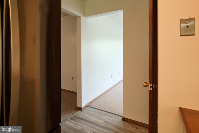 hall with baseboards, carpet floors, and wood finished floors