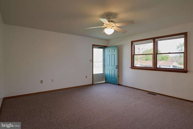 carpeted empty room with baseboards, visible vents, and ceiling fan