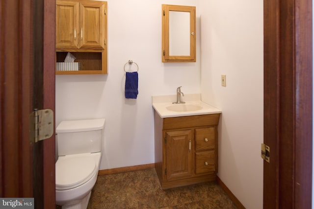 half bathroom with baseboards, toilet, and vanity