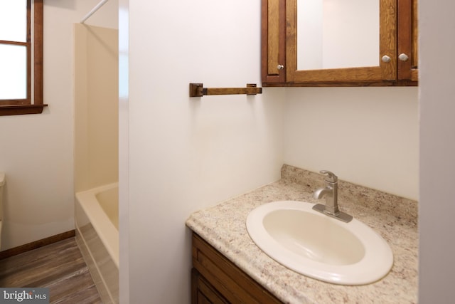 bathroom with a tub, walk in shower, wood finished floors, and vanity