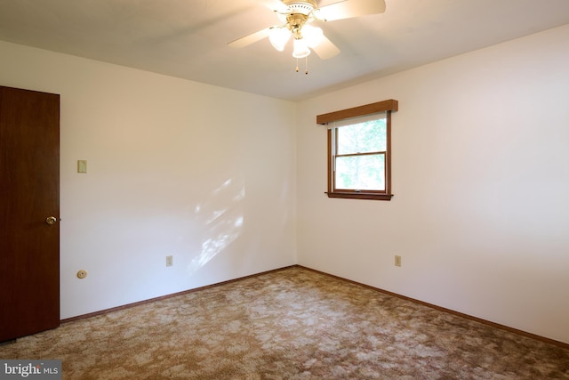 carpeted spare room featuring baseboards and a ceiling fan
