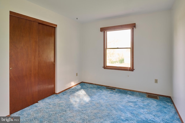 unfurnished bedroom with visible vents, carpet flooring, and a closet