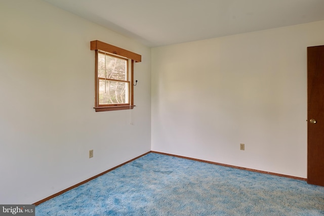 spare room featuring carpet floors and baseboards