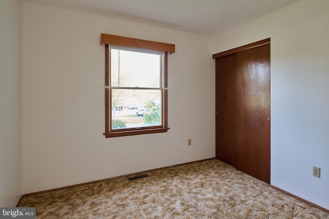 unfurnished bedroom featuring a closet, baseboards, carpet floors, and visible vents
