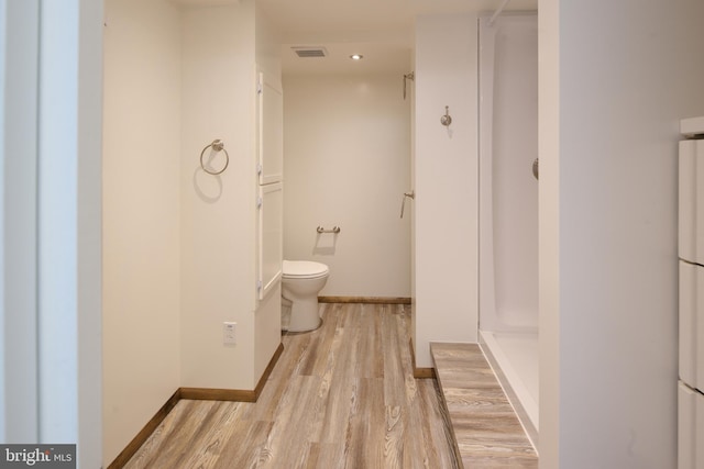 bathroom with visible vents, wood finished floors, toilet, baseboards, and a shower stall