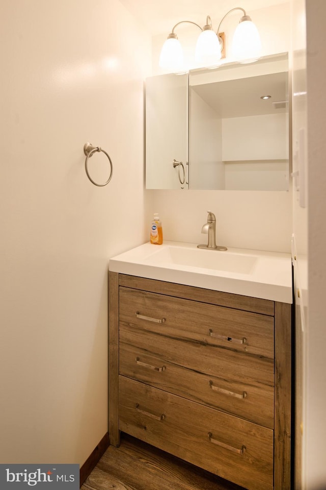 bathroom with baseboards, wood finished floors, and vanity