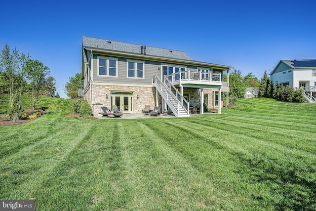 back of house with a yard, french doors, a patio area, stone siding, and a deck