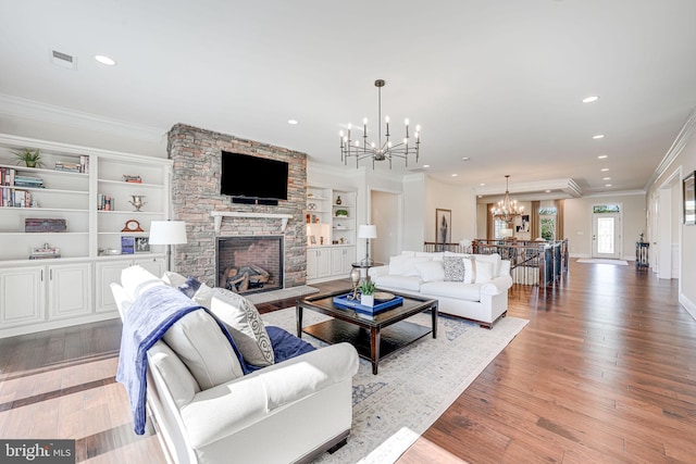 living area with crown molding, a notable chandelier, a stone fireplace, and visible vents