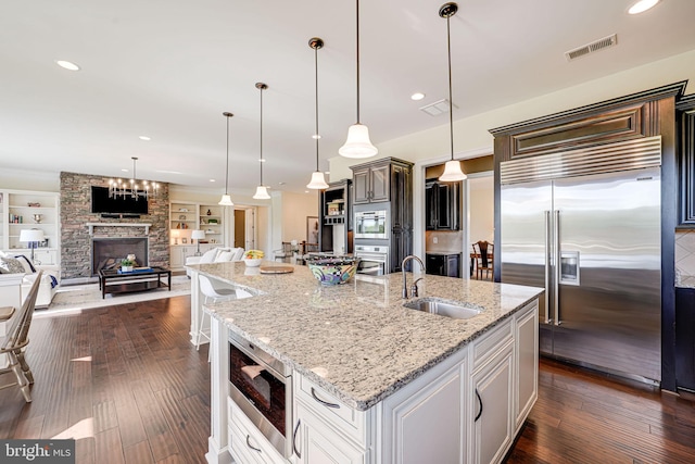 kitchen featuring a sink, built in appliances, open floor plan, and visible vents