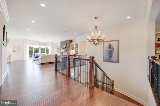 stairs with an inviting chandelier, wood finished floors, baseboards, and recessed lighting