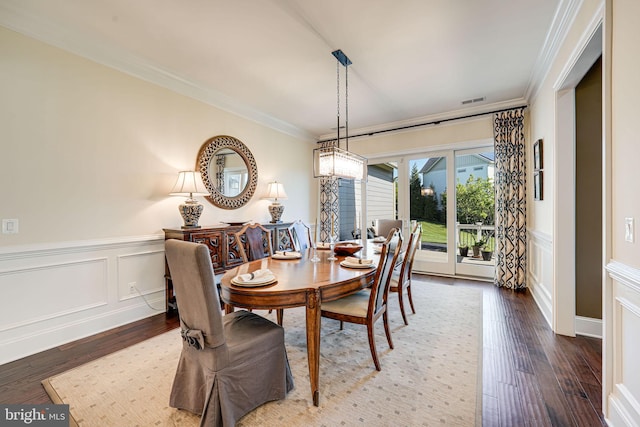 dining area with hardwood / wood-style flooring, a decorative wall, a wainscoted wall, visible vents, and crown molding
