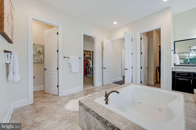 full bathroom featuring recessed lighting, baseboards, a jetted tub, vanity, and a walk in closet