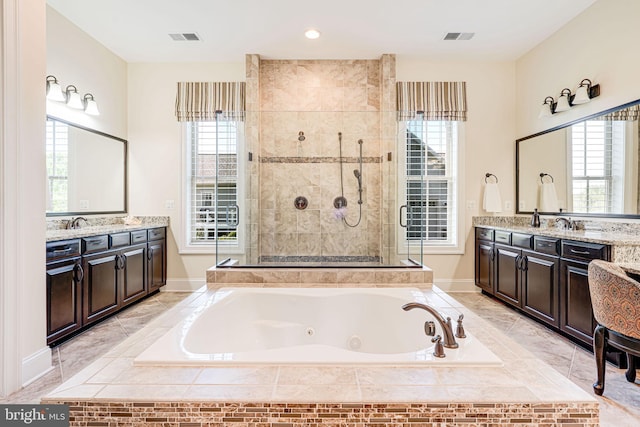 full bath with a tub with jets, two vanities, a shower stall, and visible vents