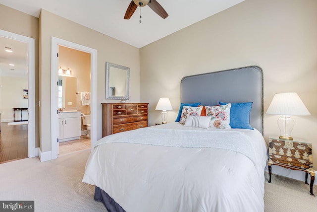 bedroom with light carpet, ensuite bathroom, a ceiling fan, and baseboards