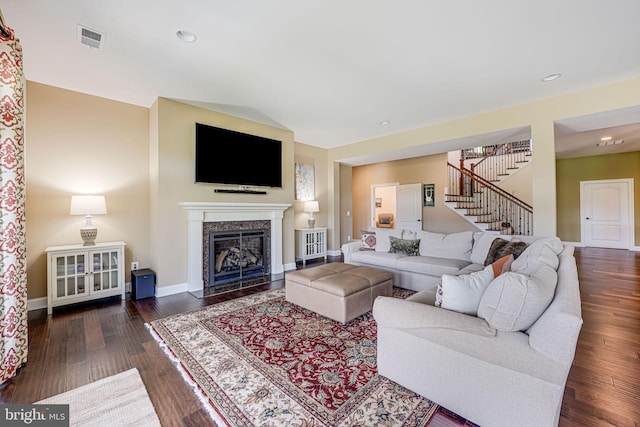 living room with baseboards, visible vents, stairs, a high end fireplace, and wood finished floors