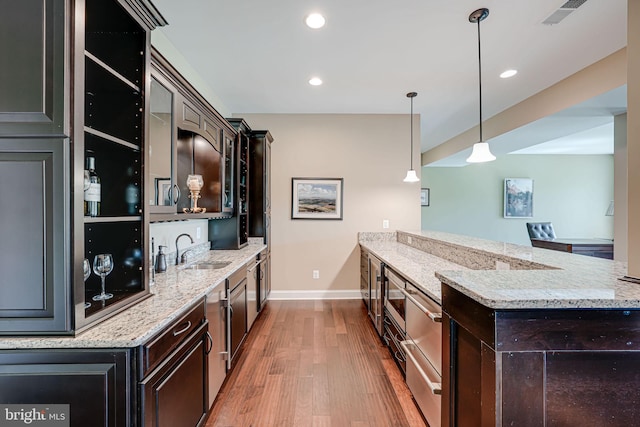 bar featuring a sink, wood finished floors, visible vents, recessed lighting, and baseboards