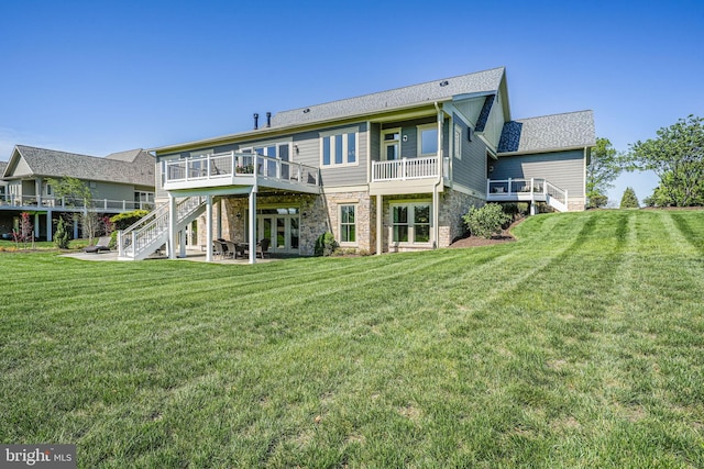 back of property with stone siding, a yard, stairway, and a deck