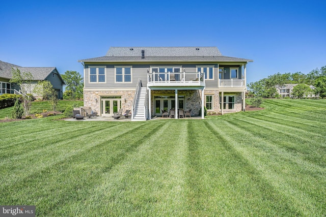 back of house featuring a patio, french doors, stone siding, and a lawn