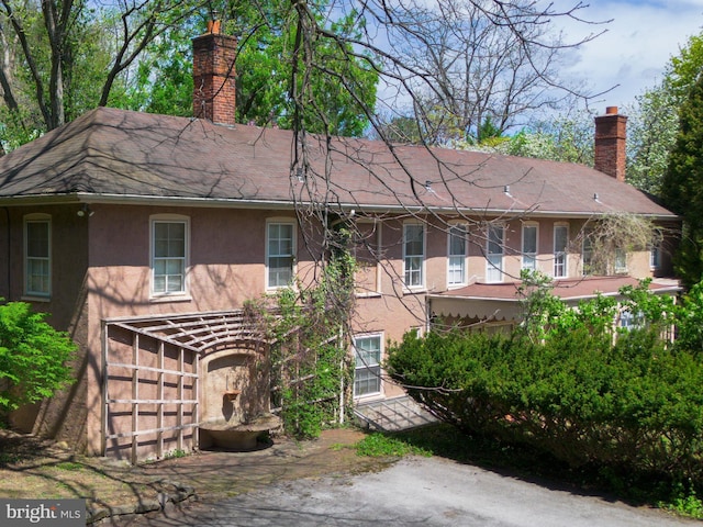 view of front facade with stucco siding and a chimney