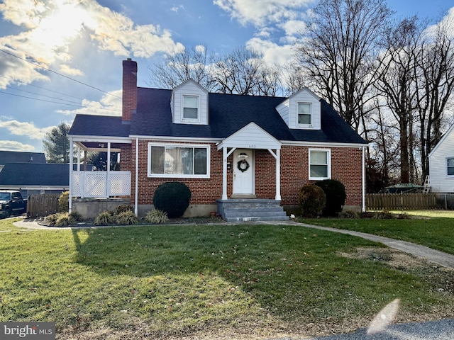 cape cod house featuring brick siding, a front lawn, and fence