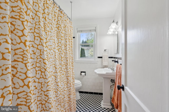 bathroom featuring a sink, tile walls, a wainscoted wall, and toilet