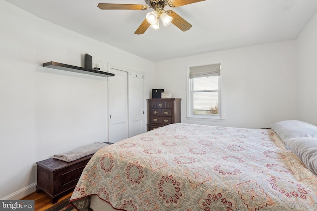 bedroom with a closet, baseboards, a ceiling fan, and wood finished floors