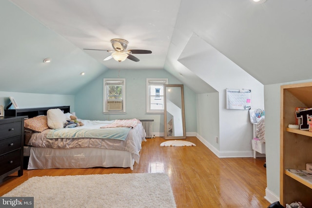 bedroom with radiator heating unit, baseboards, vaulted ceiling, and wood finished floors