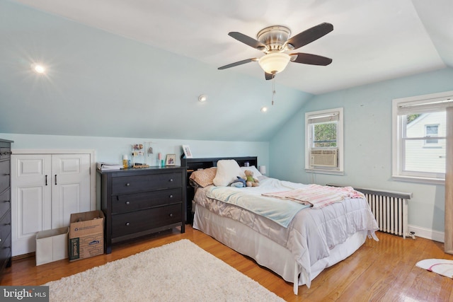 bedroom featuring radiator, wood finished floors, and lofted ceiling