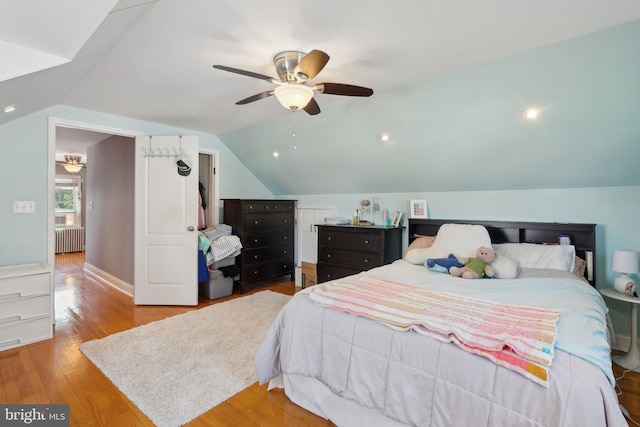 bedroom featuring wood finished floors, radiator, ceiling fan, and lofted ceiling