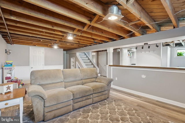 living area with stairway, a wainscoted wall, and wood finished floors
