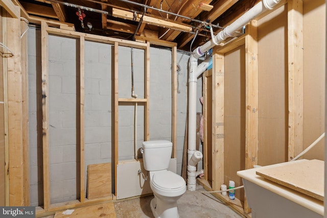 bathroom with unfinished concrete floors and toilet