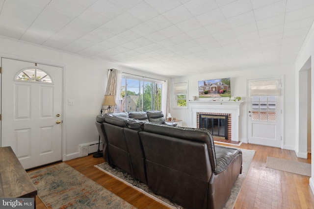 living area featuring baseboards, a brick fireplace, and wood finished floors