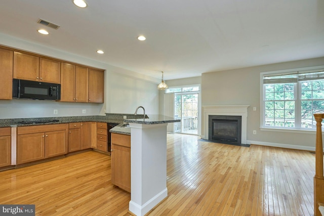 kitchen with a sink, light wood-style floors, a peninsula, visible vents, and black appliances