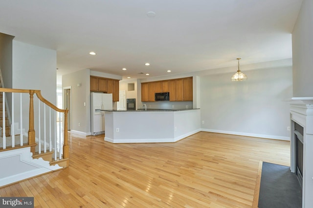 kitchen with light wood-type flooring, brown cabinetry, black appliances, and recessed lighting