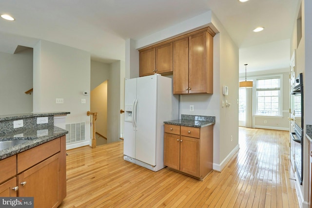 kitchen featuring visible vents, brown cabinetry, light wood-style floors, and white refrigerator with ice dispenser