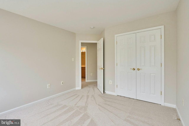 unfurnished bedroom featuring light colored carpet, baseboards, and a closet