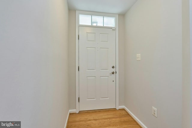 doorway to outside featuring baseboards and light wood finished floors