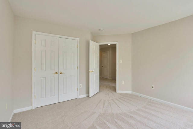 unfurnished bedroom featuring baseboards, light carpet, and a closet